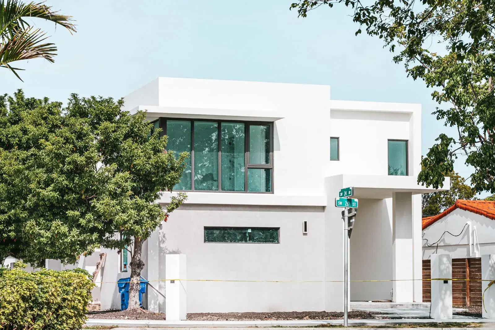 White South Florida home with large windows among palm trees